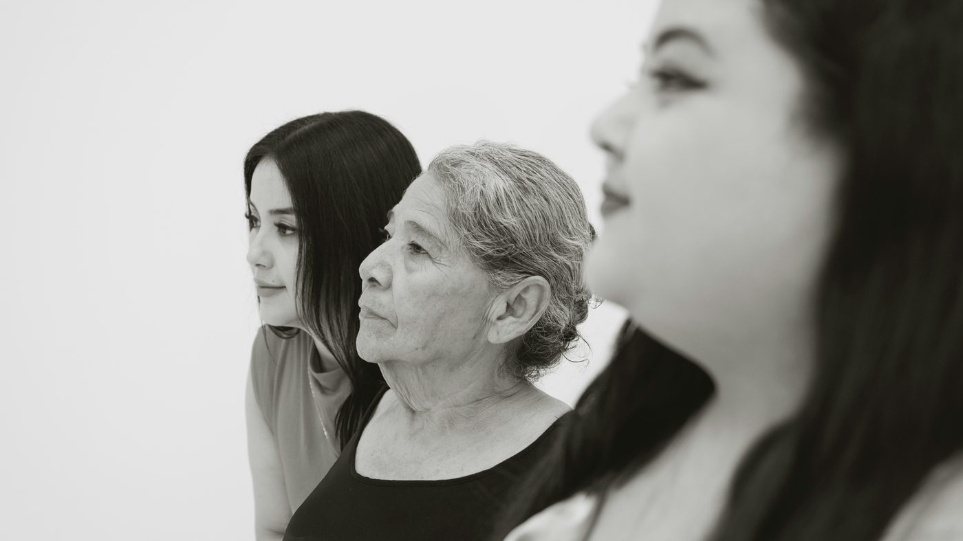 Three women of different generations, standing together in profile.